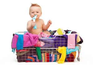 Happy toddler sitting  in basket with clothes