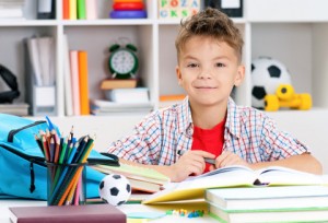 Smiling adolescent boy doing homework at the table